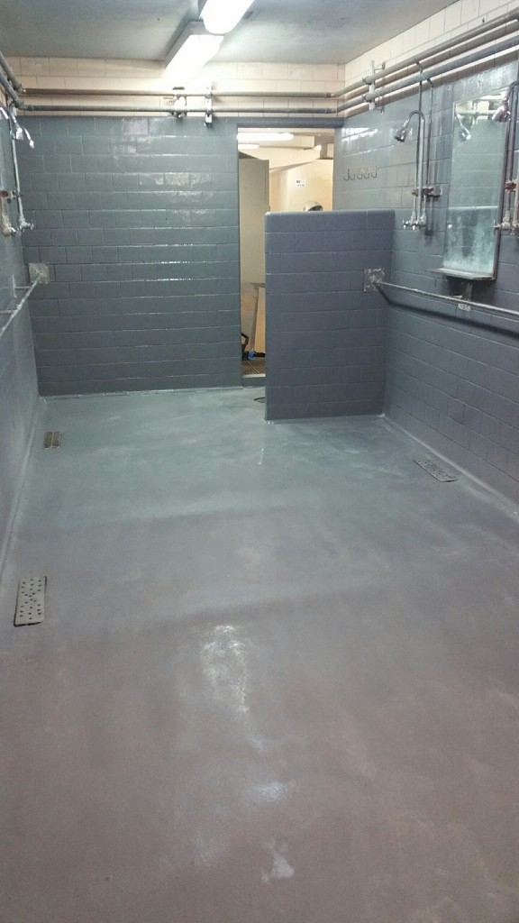 Manufacturing plant shower stall, after AMP-100 polyurea from SPI was applied, with broadcast silica sand for non-skid value.