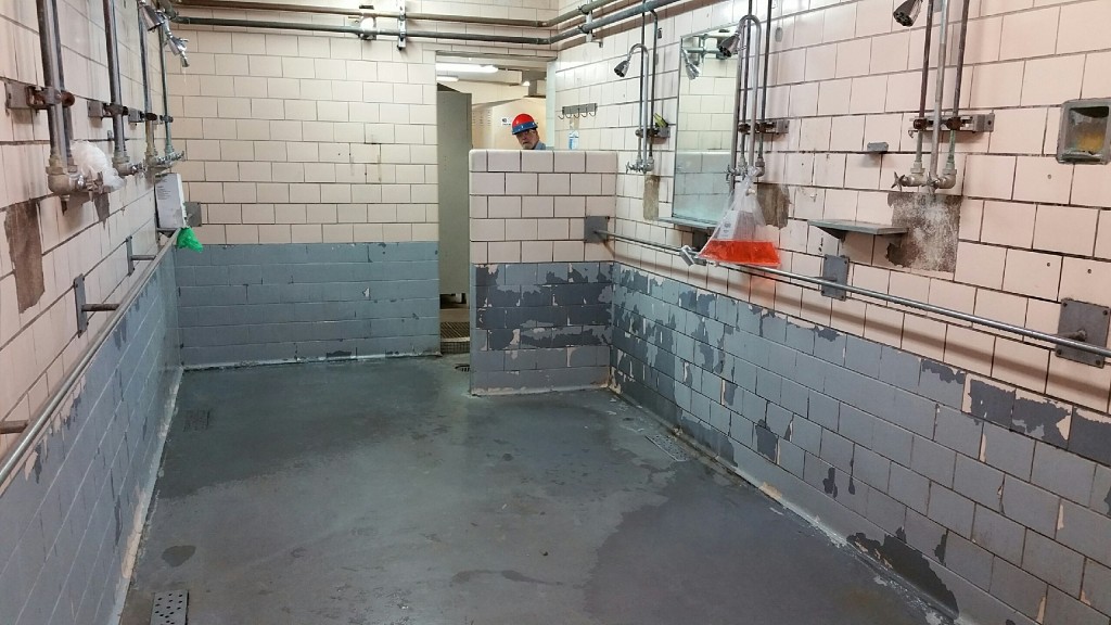 Manufacturing plant shower stall, with failing epoxy paint, before AMP-100 polyurea from SPI was applied.